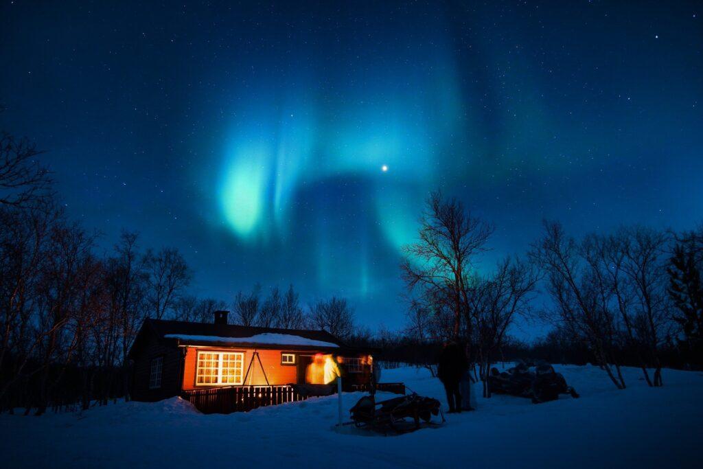 Une aurore flotte au-dessu d'un chalet en plein hiver, c'est l'image bannière de ma nouvelle : 6 jours